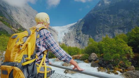 a woman traveler looks at the famous briksdal glacier in norway a back view