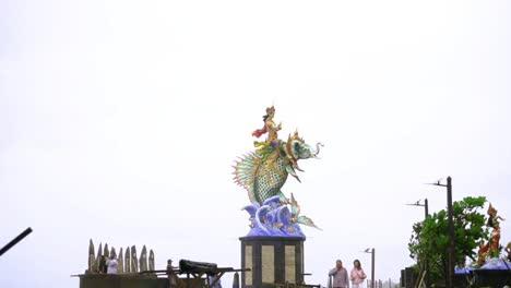 estatua de gajah mina en la playa pererena con turistas caminando en un día lluvioso