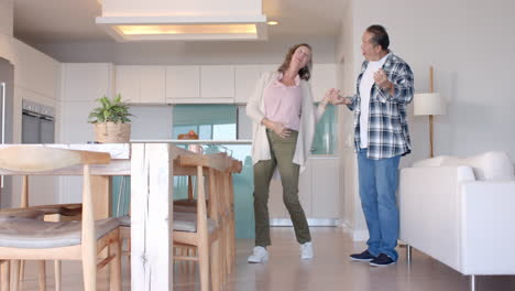 dancing together, senior couple enjoying time in modern kitchen at home, copy space