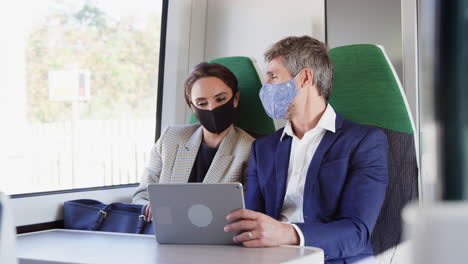 Mujer-De-Negocios-Y-Hombre-De-Negocios-En-Tren-Usando-Tableta-Digital-Con-Máscara-Facial-Ppe-Durante-La-Pandemia