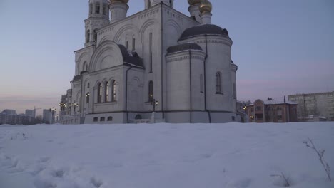 una iglesia blanca con cúpulas doradas en la nieve