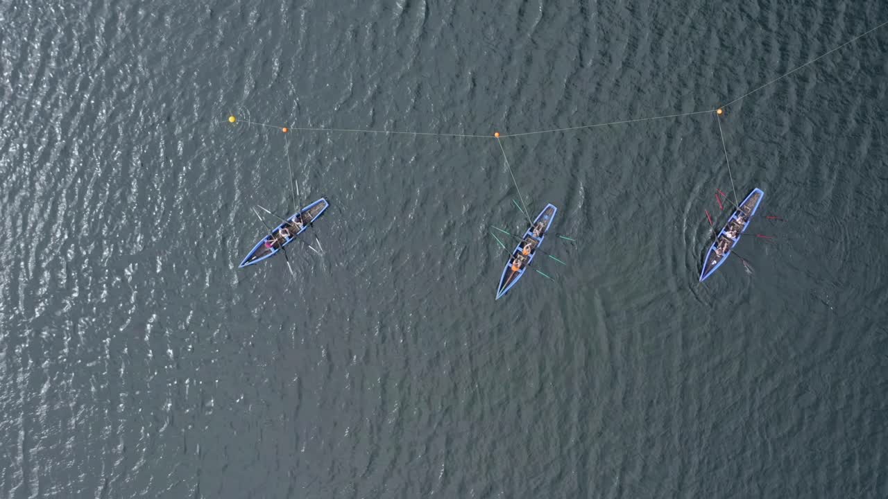 Top down bird's eye view static shot of currach irish boats in open ocean water ripples shine