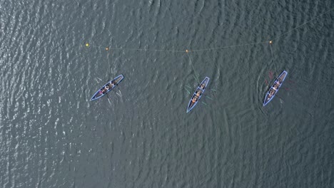 top down bird's eye view static shot of currach irish boats in open ocean water ripples shine