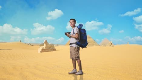 full body side view of asian male hiker with mountaineering backpack smiling and holding a camera in his hands then looking around while traveling in pyramid of giza