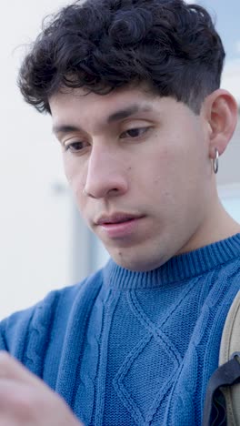 young man expressing six different emotions while looking at smartphone. vertical