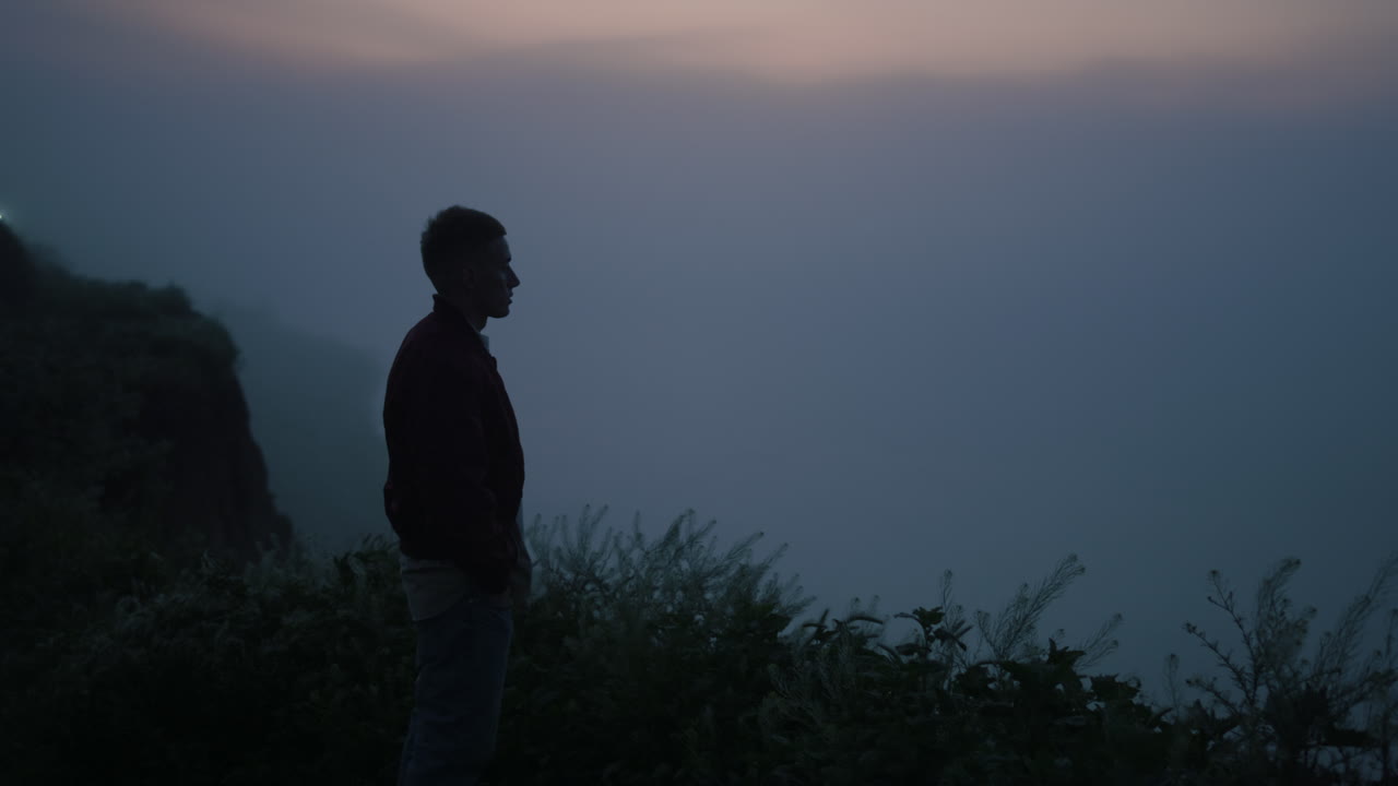 Uomo solitario che cammina in montagna all'alba. Ragazzo rilassato in piedi su una costa rocciosa.