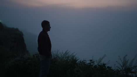 lonely man walking on mountain at sunrise. relaxed guy standing on rocky coast