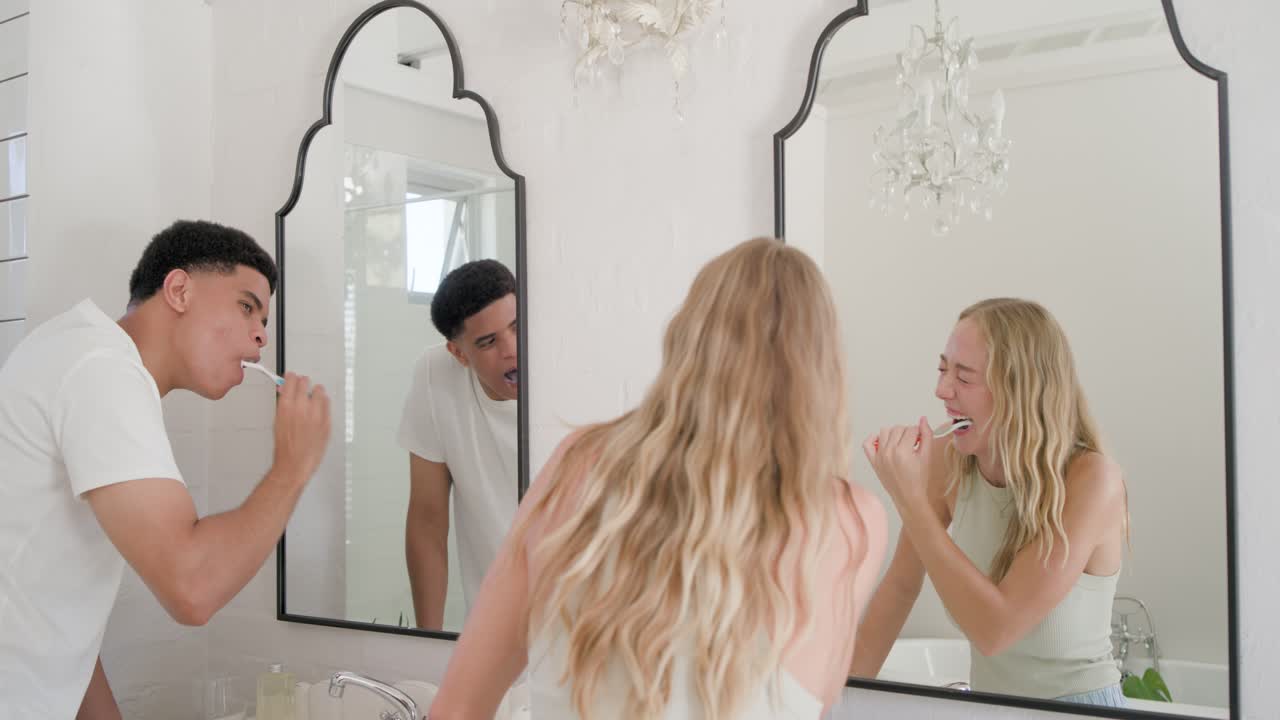 Coppia che inizia la routine mattutina lavandosi i denti con gli spazzolini davanti allo specchio del bagno.