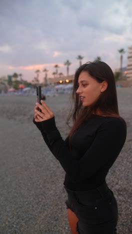 woman taking a photo on a beach at sunset