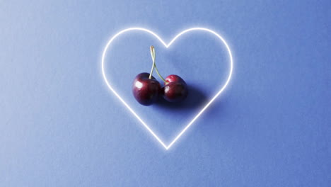 composition of cherries and neon heart shape over blue background