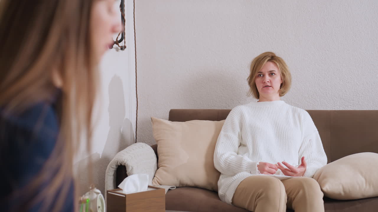Healing companion seated on sofa engaged in conversation with counselor, who listens and takes notes with focus, capturing atmosphere of therapeutic exchange and supportive guidance