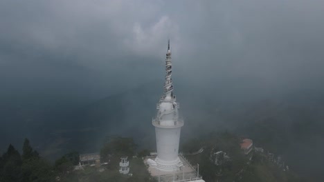 white narrow spiral stairs on the ambuluwawa tower in sri lanka filled with several tourists who enjoy the view, which is partly shrouded in a cloud cover. backwards drone tilt shot