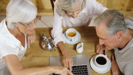 senior friends discussing over a laptop in cafe 4k