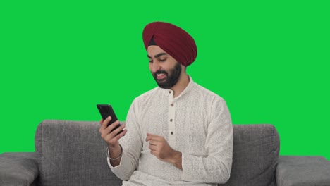 Glücklicher-Sikh-Indianer,-Der-Auf-Dem-Grünen-Bildschirm-Des-Telefons-Scrollt