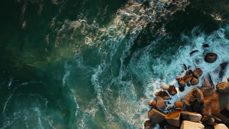 aerial showing rocks and surfers waiting for the next big wave in llandudno, cape town, south africa