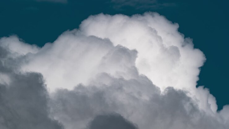 Thick fluffy clouds getting bigger, they are expanding into the atmosphere like a huge balloons changing their color from white to yellow, and grey
