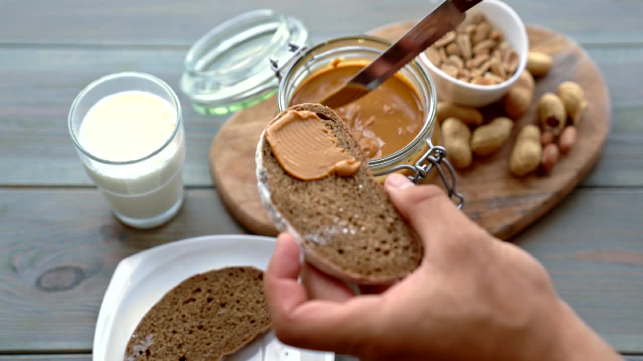 Closeup of male hand making sandwich with peanut butter