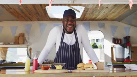 portrait of african american man wearing apron smiling while standing in the food truck