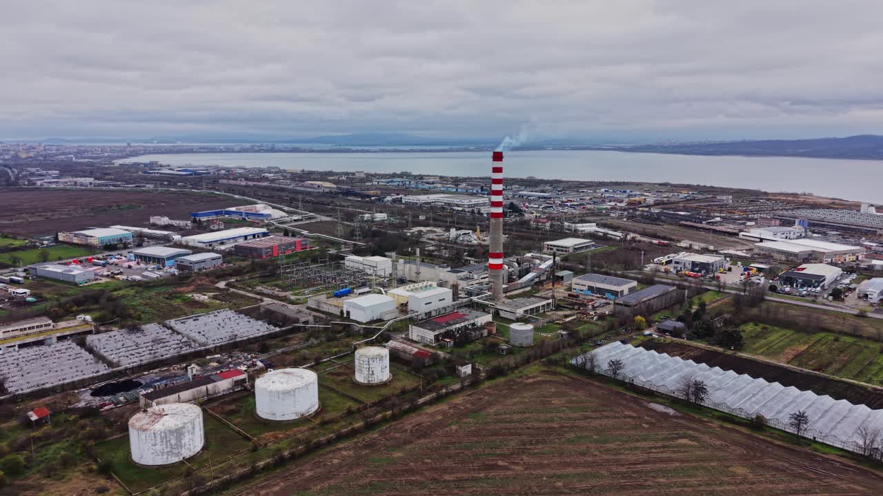 Industrial complex near water with smokestack and storage tanks