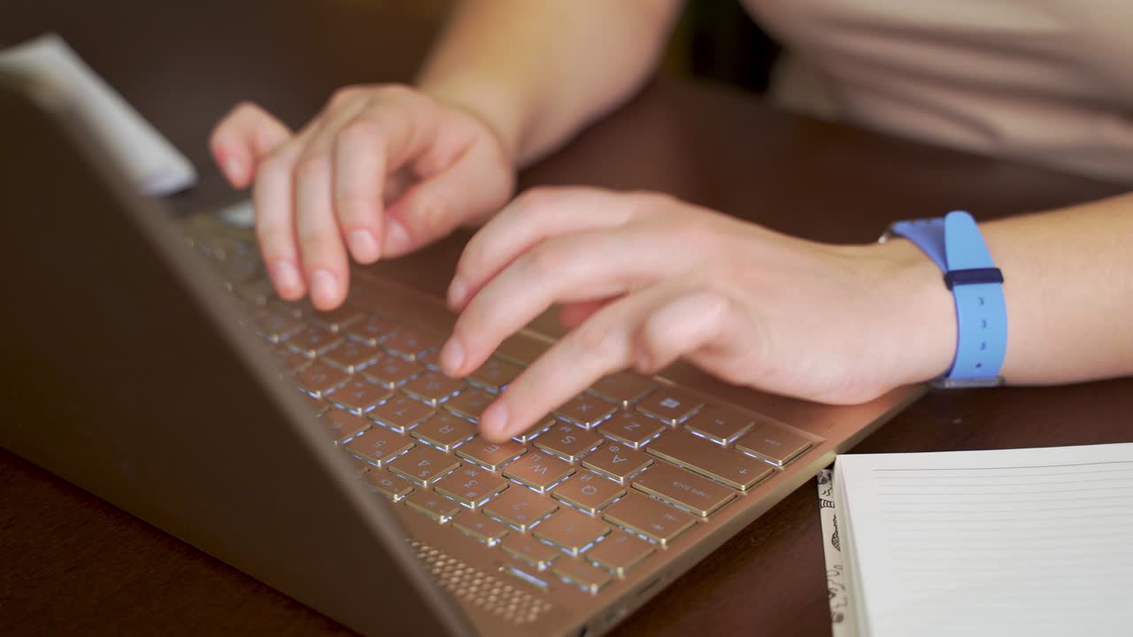 Female hands are typing text on laptop keyboard. Fingers quickly press the keys on the keyboard. There is notebook next to it. Personal computer, remote work at home, business, study, messaging, chat