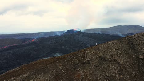 vista aérea sobre la gente que mira la erupción del volcán fagradalsfjall en islandia - disparo de drones