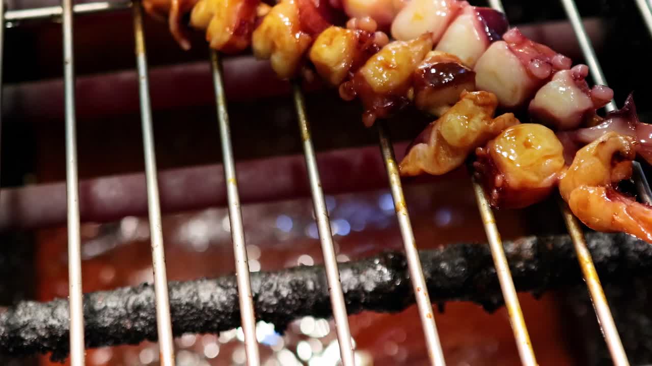 Close-up of a brush applying sauce to squid skewers on a grill, highlighting texture and glaze.