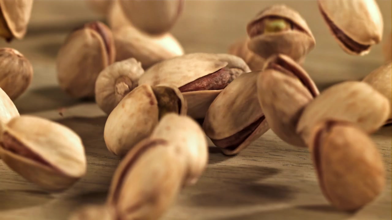 Pistachio Nuts Falling and Scattering on a Wooden Surface in Slow Motion
