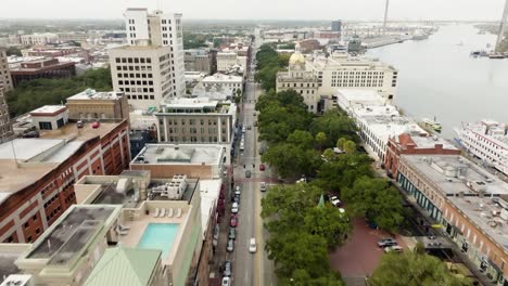 Drone-of-Savannah-Georgia-riverfront-area-along-the-river-with-cars-and-boats-on-an-overcast-day-over-road-with-Talmadge-Memorial-Bridge