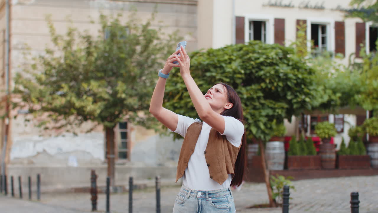 Frustrated young woman trying to catch signal on smartphone for better connection in city street