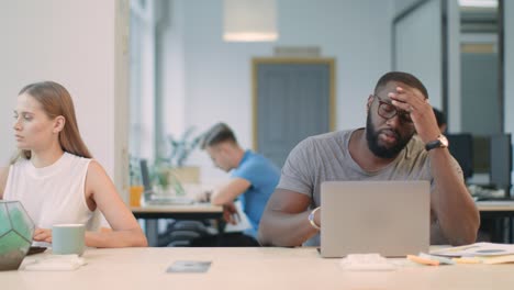 young man reading bad news on laptop computer in office. shocked african person