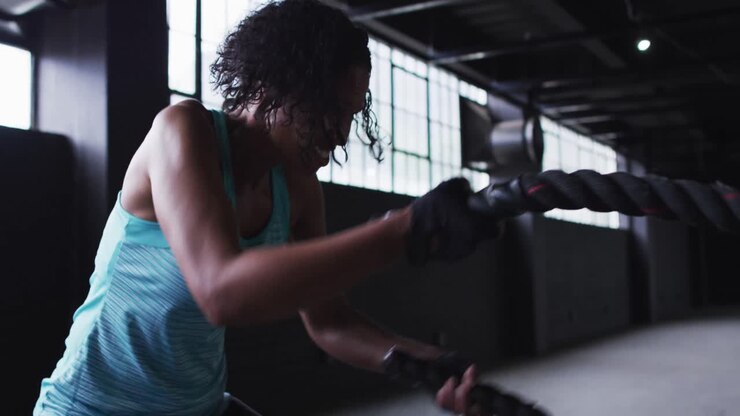 African american woman exercising battling ropes in an empty urban building