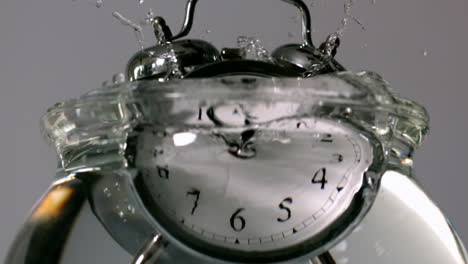 alarm clock falling into bowl of water