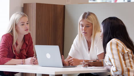 Gruppe-Junger-Geschäftsfrauen,-Die-Am-Tisch-Sitzen-Und-An-Der-Aufgabe-Mit-Einem-Laptop-Am-Tag-Der-Rekrutierungsbewertung-Für-Absolventen-Zusammenarbeiten