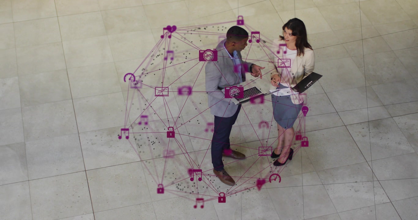 Coworkers opening laptop and tapping tablet in lobby while pink network sphere forming for business