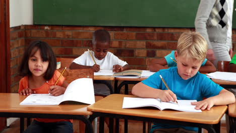 pupils working while teacher walks around classroom