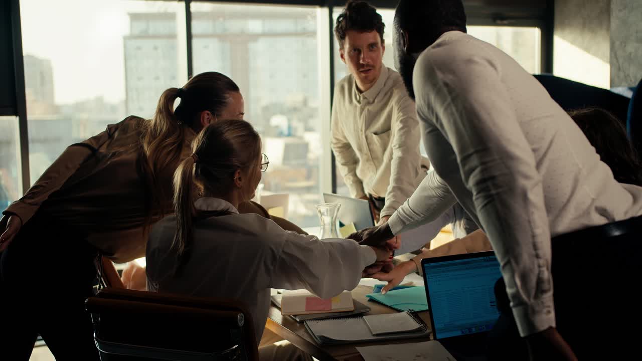 un equipo unido de trabajadores de oficina ponen sus manos juntas y las levantan. manteniendo la moral de un equipo de trabajadores de oficina