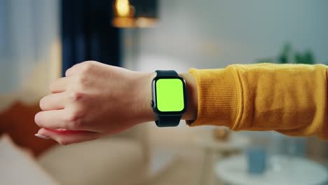 mujer usando un reloj inteligente con una llave de croma de primer plano. joven mujer usando un brazalete de fitness con un primer plano de pantalla verde.