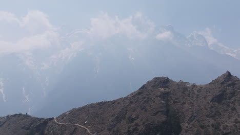 aerial landscape of high hills and mountains enveloped by dense clouds caused by air pollution in nepal himalayas, revealing trekking trails and tourism adventure