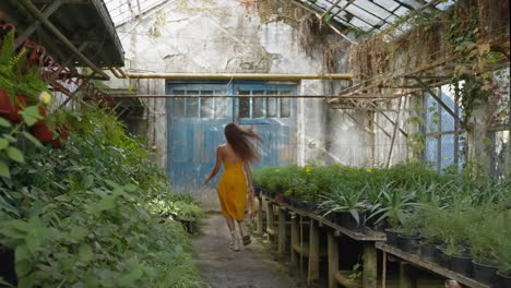 woman walking through an abandoned greenhouse