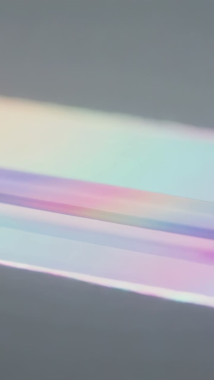 Vertical video: Sliding hinge pulling iridescent panel over gray table, showing rainbow, copy space