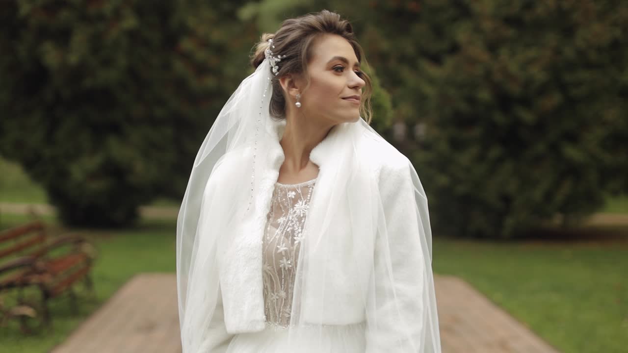 Bellissima sposa in abito bianco che sorride e guarda la fotocamera
