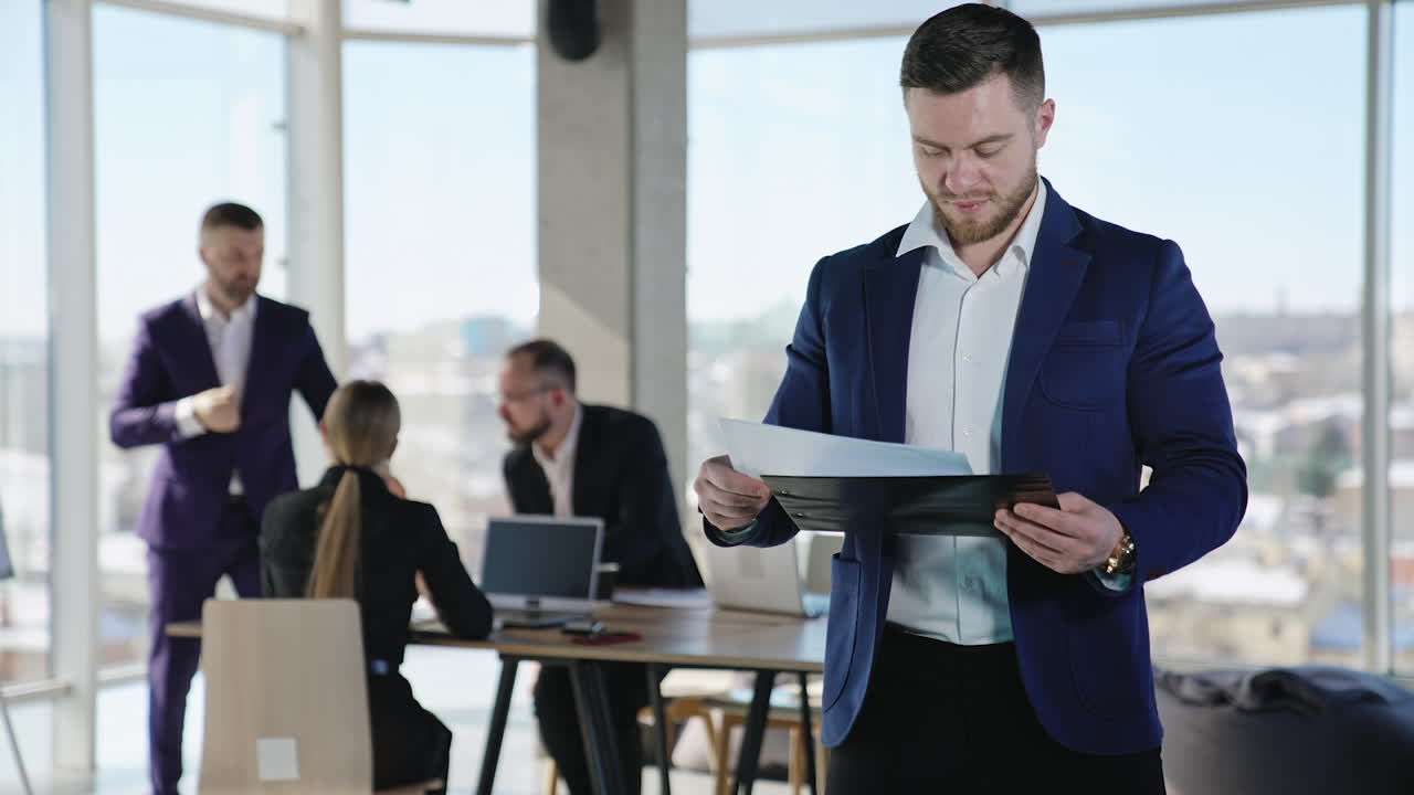 Young businessman checking the information in papers and then throws them away. Portrait of a confident male wearing suit. Business team working at the backdrop.