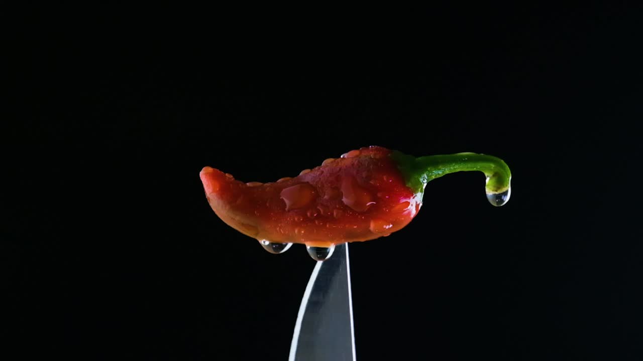 주방 칼의 끝에 작은 칠리 고추 물방울에 여 검은색에 떨어지는 칠리