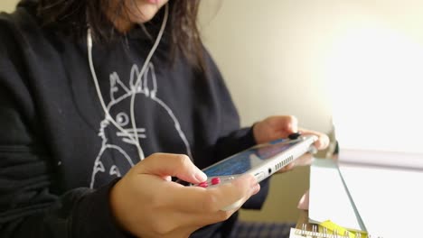 Close-up-shot-of-a-teenager-girl-with-black-hair-in-hoodie-playing-Nintendo-Switch