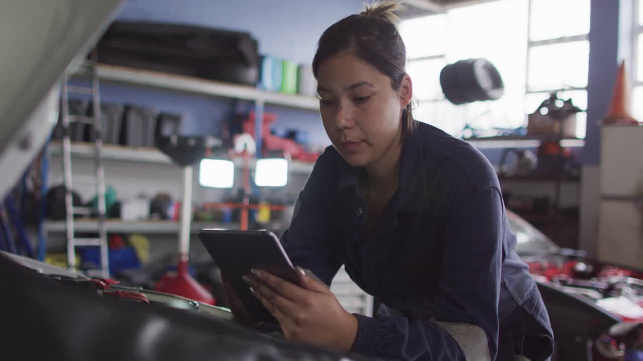 mecánica usando una tableta digital e inspeccionando el automóvil en una estación de servicio de automóviles