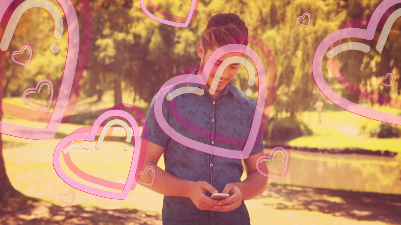 Using smartphone in park, animated hearts overlaying screen for young man