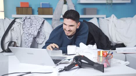 un joven perezoso y feliz usando una computadora portátil en casa.