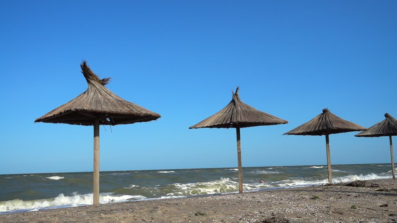 Ombrelloni di paglia e onde del mare. Movimento lento
