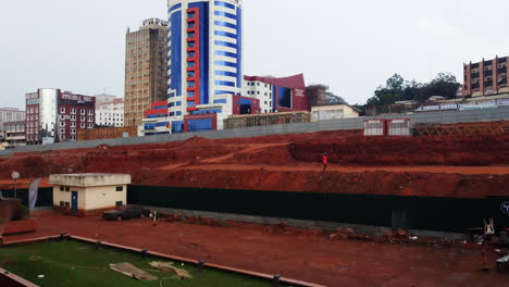descending drone shot of a construction site in front of the general delegation of taxes building, in cloudy yaounde, cameroon