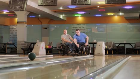 two young disabled men in wheelchairs playing bowling in the club